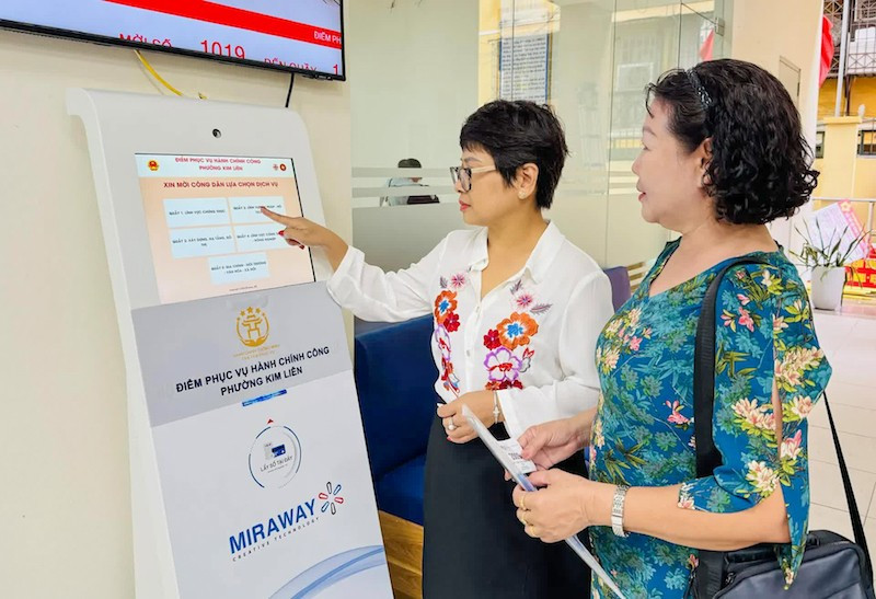 Công chức tại Điểm tiếp nhận, phục vụ hành chính công phường Kim Liên hướng dẫn người dân lấy số để thực hiện các thủ tục hành chính. (Ảnh KHÁNH HUY) img-0793.jpg