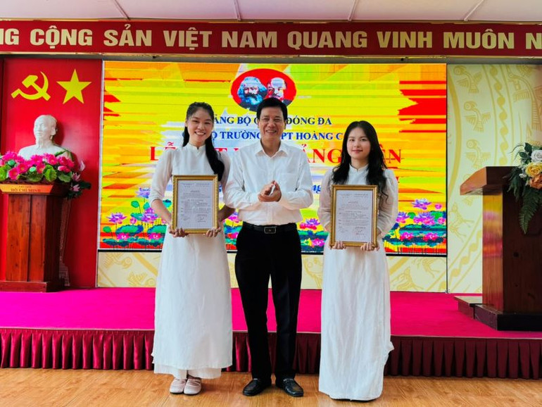 Phó Bí thư Thường trực Quận ủy Đống Đa Nguyễn Anh Cường trao quyết định kết nạp đảng viên cho hai học sinh ưu tú Trường THPT Hoàng Cầu.