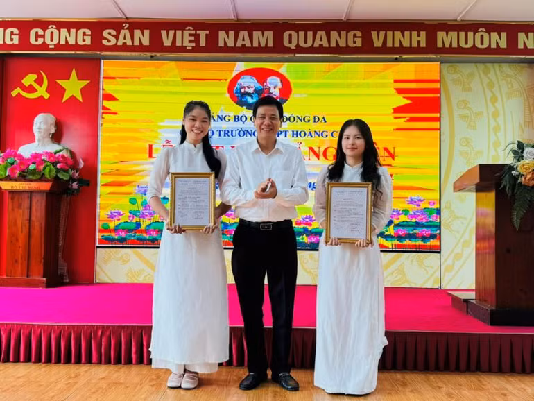 Phó Bí thư Thường trực Quận ủy Đống Đa Nguyễn Anh Cường trao quyết định kết nạp đảng viên cho hai học sinh ưu tú Trường THPT Hoàng Cầu.