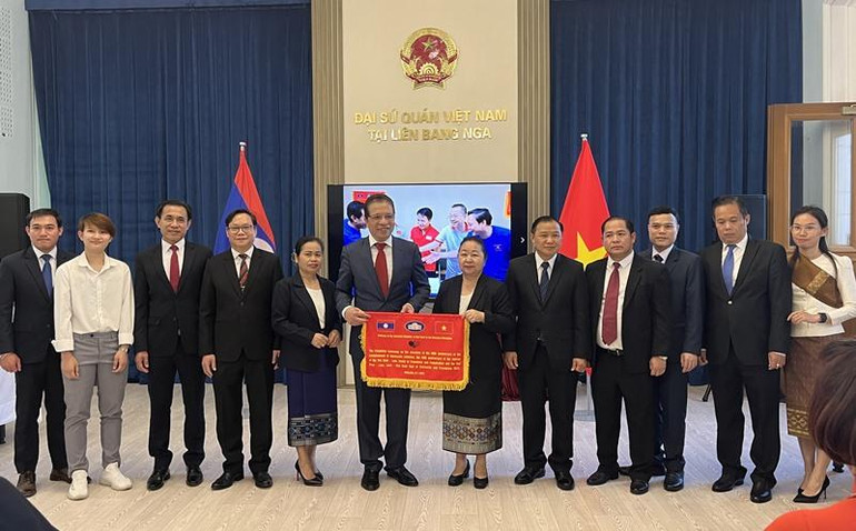 Đại sứ Việt Nam Đặng Minh Khôi trao cờ lưu niệm và chụp ảnh cùng Đại sứ Vilavanh Yiapoher và cán bộ Ngoại giao Lào đang công tác tại Nga. (Ảnh: QUẾ ANH)