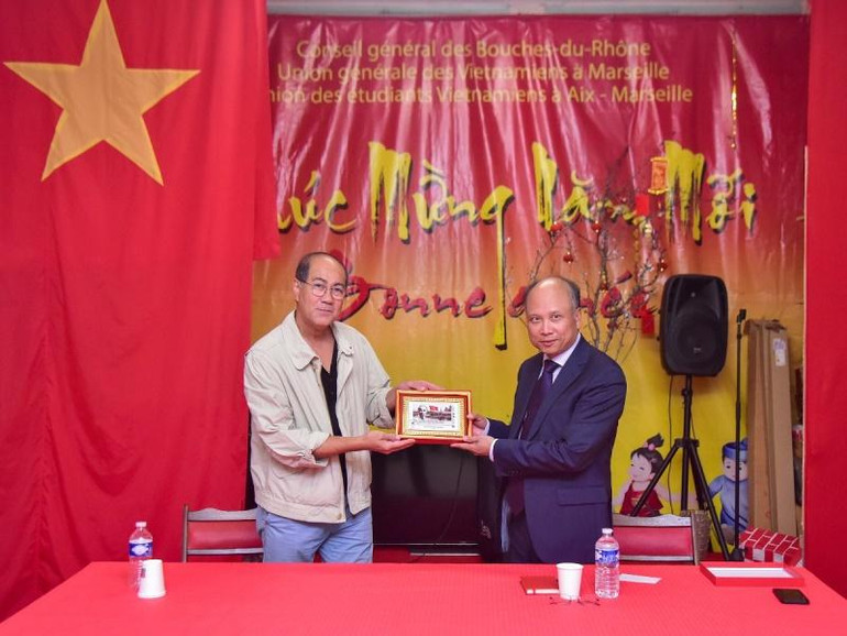 Đại sứ Đinh Toàn Thắng trao tặng bức tranh tem Chủ tịch Hồ Chí Minh do Bưu điện Pháp phát hành nhân dịp kỷ niệm 100 năm Người đặt chân đến Pháp cho Hội người Việt tại Marseille. (Ảnh: MINH DUY)