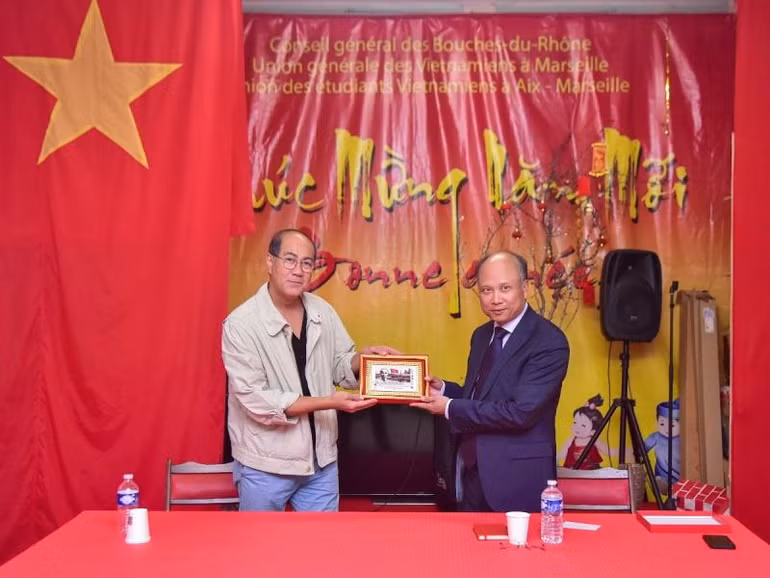 Đại sứ Đinh Toàn Thắng trao tặng bức tranh tem Chủ tịch Hồ Chí Minh do Bưu điện Pháp phát hành nhân dịp kỷ niệm 100 năm Người đặt chân đến Pháp cho Hội người Việt tại Marseille. (Ảnh: MINH DUY)