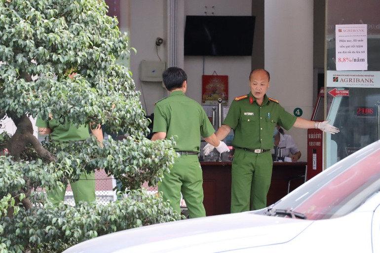 Lực lượng kỹ thuật hình sự tiến hành khám nghiệm khu vực trong quầy giao dịch.