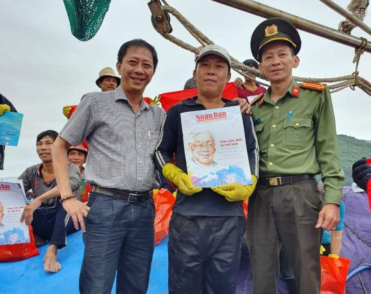 Ông Đào Xuân Thiện (trái) - Giám đốc Ban Quản lý Cảng cá tỉnh Bình Định và đại diện lãnh đạo Đội Quản lý nông-lâm-ngư nghiệp (Công an Bình Định) tặng báo Nhân Dân Xuân Quý Mão 2023 cho ngư dân vươn khơi bám biển xuyên Tết Nguyên đán 2023.