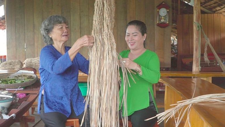 Bà Bàn Thị Xiếu đang hướng dẫn khách đan võng dây chuối. Bà Bàn Thị Xiếu đang hướng dẫn khách đan võng dây chuối.