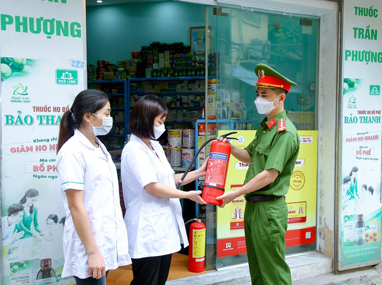 Công an phường Khương Đình (Thanh Xuân, Hà Nội) hướng dẫn người dân sử dụng bình cứu hỏa. (Ảnh: Huy Hoàng)