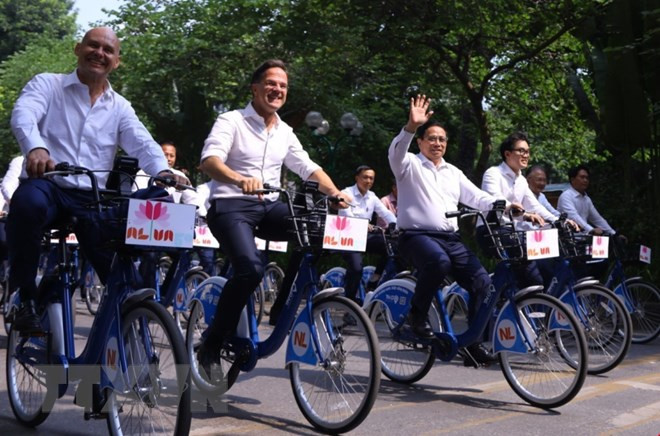 Thủ tướng Phạm Minh Chính cùng Thủ tướng Hà Lan Mark Rutte đạp xe trên đường phố Hà Nội. (Ảnh: Văn Điệp/TTXVN)