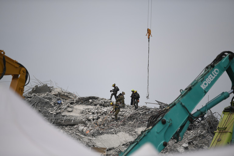 Cận cảnh nhân viên cứu hộ đang tìm kiếm các nạn nhân trên đỉnh đống bê tông, sắt thép cao hơn tòa nhà 5 tầng.