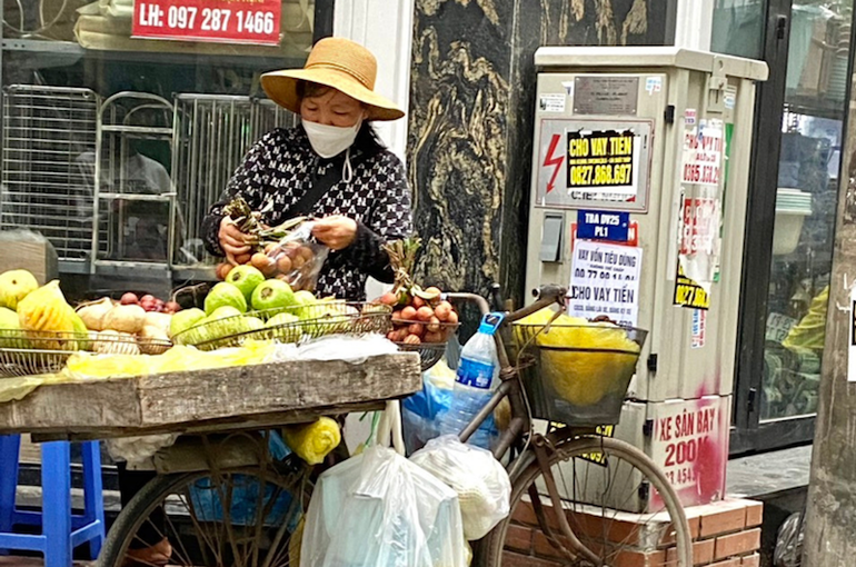 Người bán hàng bất chấp nguy hiểm đứng cạnh bốt điện để bán hàng. Người bán hàng bất chấp nguy hiểm đứng cạnh bốt điện để bán hàng.
