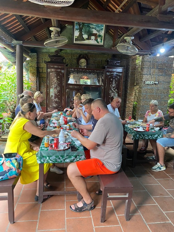 Khách du lịch nước ngoài thưởng thức ẩm thực truyền thống trong không gian nhà cổ tại Làng cổ Đường Lâm. (Ảnh: Trọng An)