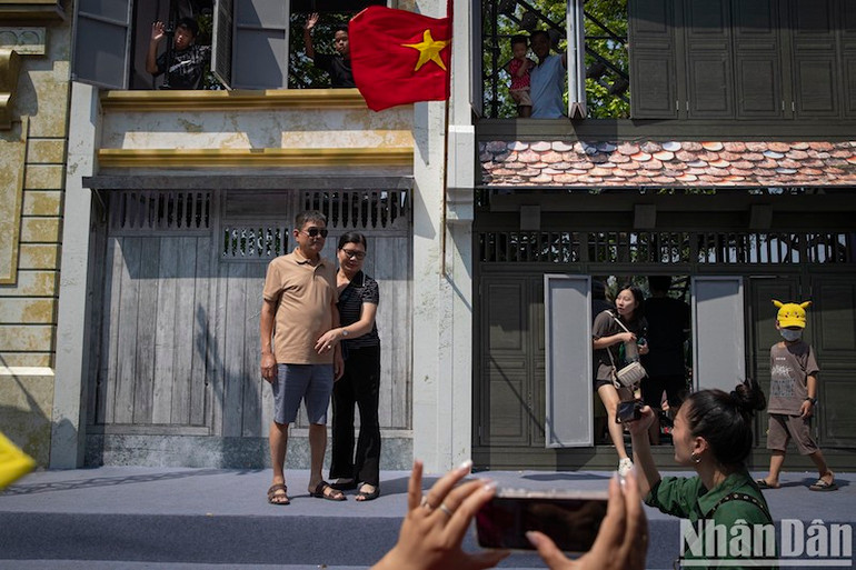 Người dân chụp ảnh trước mô hình nhà trên phố cổ được lắp dựng tại khu vực hồ Hoàn Kiếm. (Ảnh: Sơn Tùng)