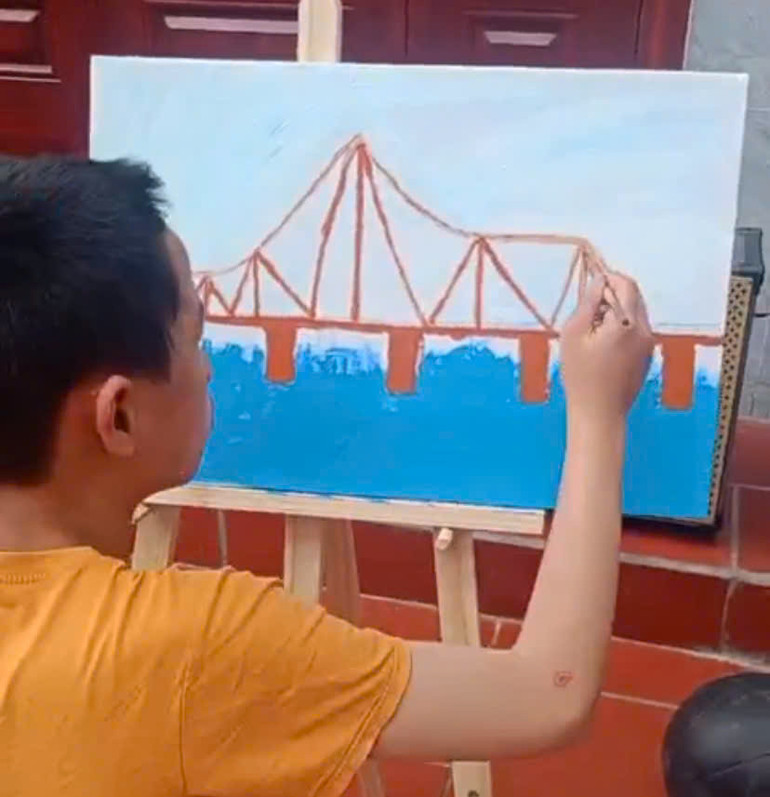 Cậu bé Tạ Đức Bảo Nam say sưa vẽ cầu. (Ảnh: VĂN CHỨC)