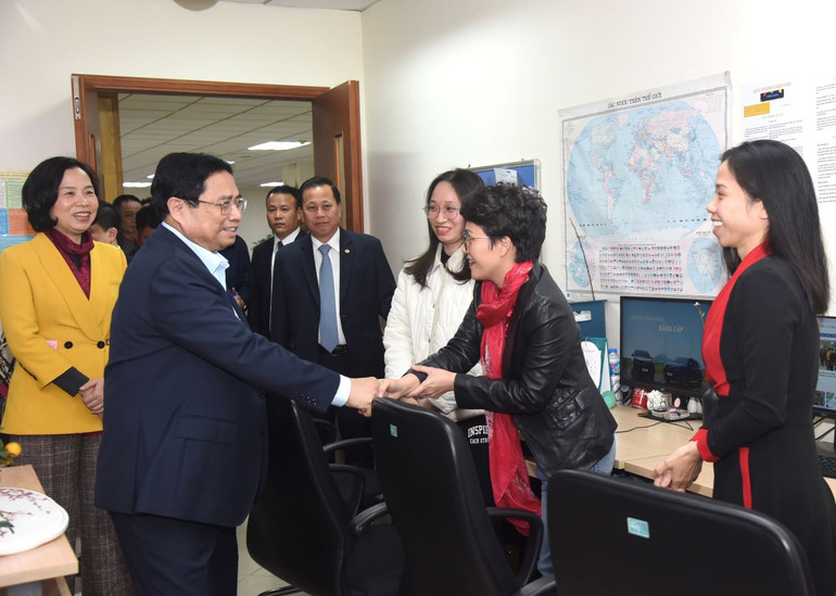 Thủ tướng Phạm Minh Chính thăm hỏi và động viên cán bộ công nhân viên Ban biên tập tin Thế giới (TTXVN) đang trực Tết. (Ảnh: TRẦN HẢI)