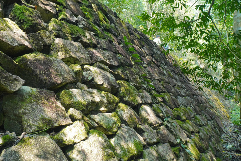 Một đoạn kè đường xếp đá nằm sâu trong rừng già vẫn sừng sững trước gió sương. (Ảnh: NGỌC TÚ)