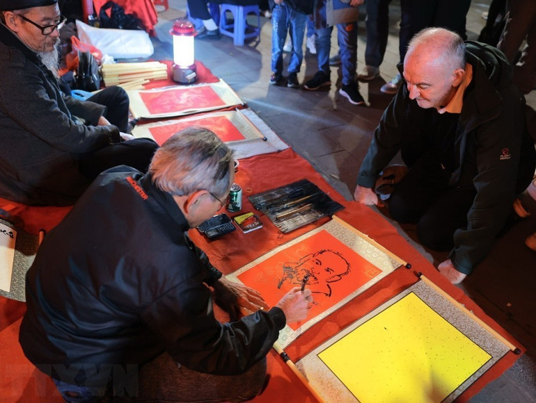 Du khách quốc tế xin chữ, xin tranh ông đồ để cầu một năm mới bình an, nhiều may mắn. (Ảnh: Hoàng Hiếu/TTXVN)