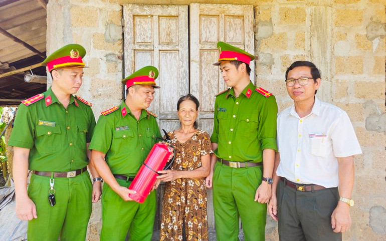 Công an xã chính quy xã Triệu Giang, huyện Triệu Phong tặng bình chữa cháy cho bà Hồ Thị Thúy, hộ nghèo của địa phương.