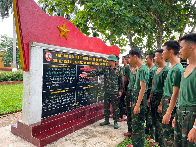 Thiếu tá Trần Đặng Tiến, Chính trị viên Tiểu đoàn 8, Trung đoàn 18, Sư đoàn 325, Quân đoàn 12 (Bộ Quốc phòng) giới thiệu với bộ đội lời Bác Hồ dạy ngày này năm xưa trên Bảng tin thi đua của đơn vị. Ảnh: Đức Truyền.
