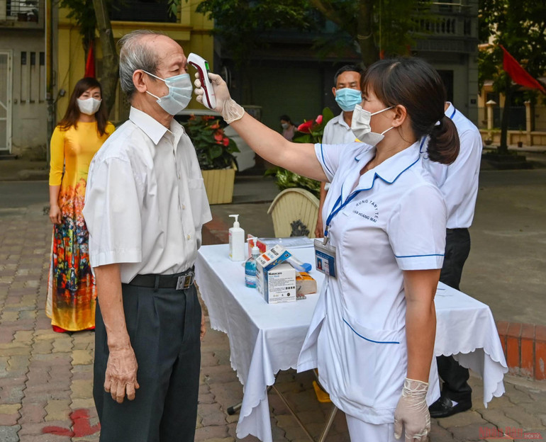Các cử tri được tiến hành kiểm tra thân nhiệt trước khi vào khu vực bỏ phiếu. 7_bau_cu-1621729278543.jpeg