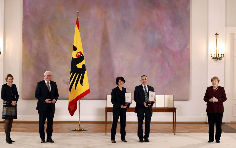 Tổng thống Đức Frank-Walter Steinmeier trao Huân chương Danh dự cho cặp vợ chồng nhà khoa học Ozlem Tureci và Ugur Sahin dưới sự chứng kiến của Thủ tướng Đức, bà Angela Merkel. Ảnh: AP. Cặp vợ chồng nhà khoa học sáng lập BioNTech: Mục tiêu tiếp theo là vaccine ngừa ung thư -0