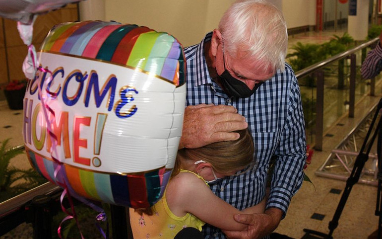 Bé Charlotte Roempke, 8 tuổi, đoàn tụ với ông của cô bé sáng 21/2 tại sân bay Sydney (Ảnh: REUTERS) Australia chính thức chào đón du khách quốc tế trở lại -0