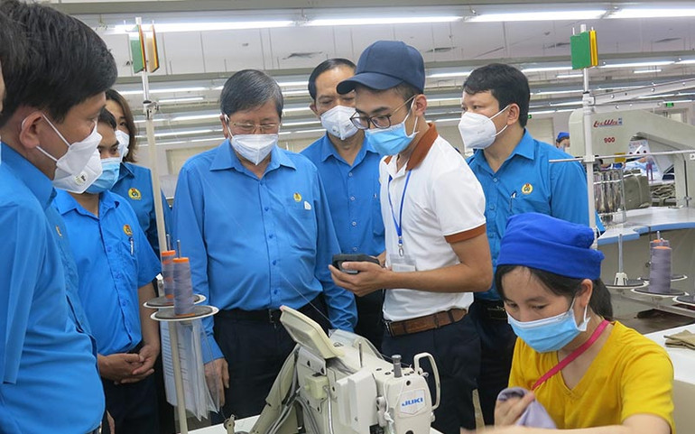 Anh Hoàng Văn Giang (áo trắng), nhân viên quản lý nguyên liệu Công ty TNHH Sakurai Việt Nam (Thanh Hóa) trao đổi về sáng kiến thiết kế phần mềm quản lý tồn kho máy may công nghiệp. (Ảnh NGỌC TÚ) Một triệu sáng kiến vượt khó, chiến thắng đại dịch -0