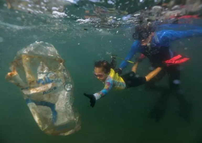 Bé Nina Gomes, 4 tuổi, cùng với cha là nhà sinh vật biển, dọn rác thải nhựa tại bãi biển Praia Vermelha ở Rio de Janeiro, Brazil hồi tháng 7. (Ảnh: Reuters) 10 bức ảnh ấn tượng về môi trường năm 2021 -0