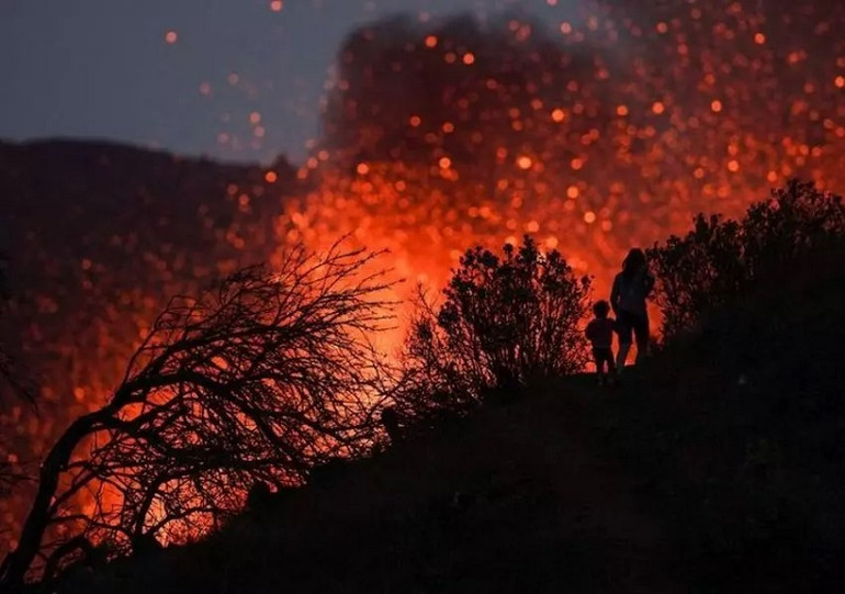 Một phụ nữ và một đứa trẻ trên sườn núi Cumbre Vieja, đảo La Palma hồi tháng 10. (Ảnh: Reuters) 10 bức ảnh ấn tượng về môi trường năm 2021 -0