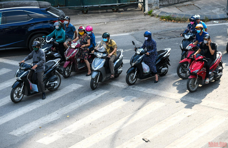 Trong lúc chờ đèn đỏ, dưới thời tiết nắng nóng như thiêu đốt, nhiều người đi đường cố len lỏi vào nơi bóng mát để tránh nóng. Người dân Hà Nội chống chọi với nắng nóng gay gắt -0