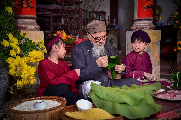 Các cháu nhỏ thì ngồi quây quần bên ông, thích thú xem ông tuốt lá dong. (Ảnh: Thành Đạt) Tái hiện hình ảnh Tết xưa – lưu giữ những giá trị truyền thống tốt đẹp -0