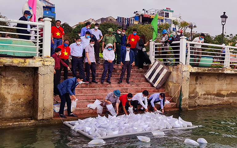 Các đại biểu thả tôm giống xuống sông Nhật Lệ để tái tạo thủy sản. Tặng 10.000 lá cờ Tổ quốc cho ngư dân Quảng Bình -0