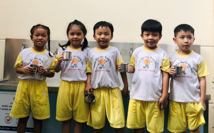 Các em học sinh bên hệ thống máy lọc nước uống sạch. “Nước sạch học đường” đến với giáo viên, học sinh huyện Bắc Bình, Bình Thuận -0