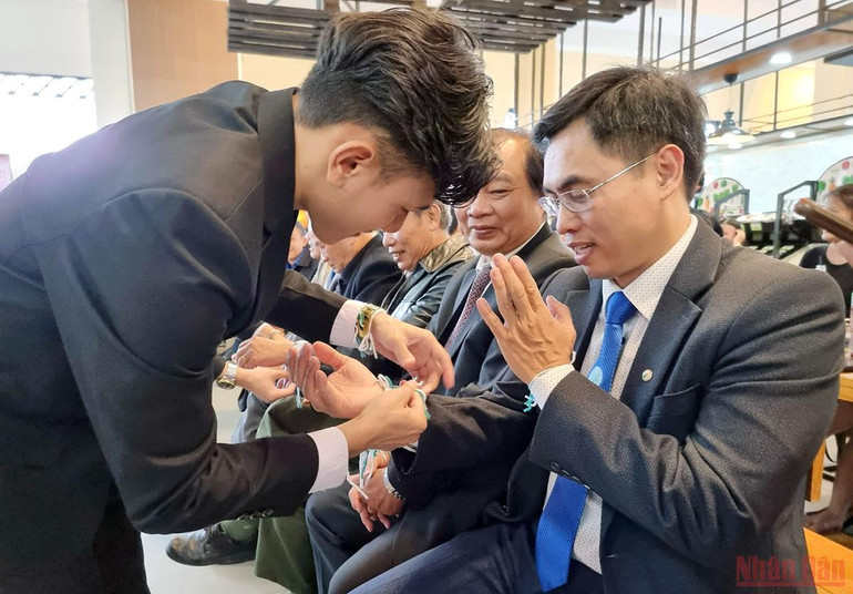 Các sinh viên Lào thực hiện lễ buộc chỉ cổ tay cho những người tham dự. Sinh viên Lào tại Trường Đại học Đà Lạt được các gia đình nhận đỡ đầu -0