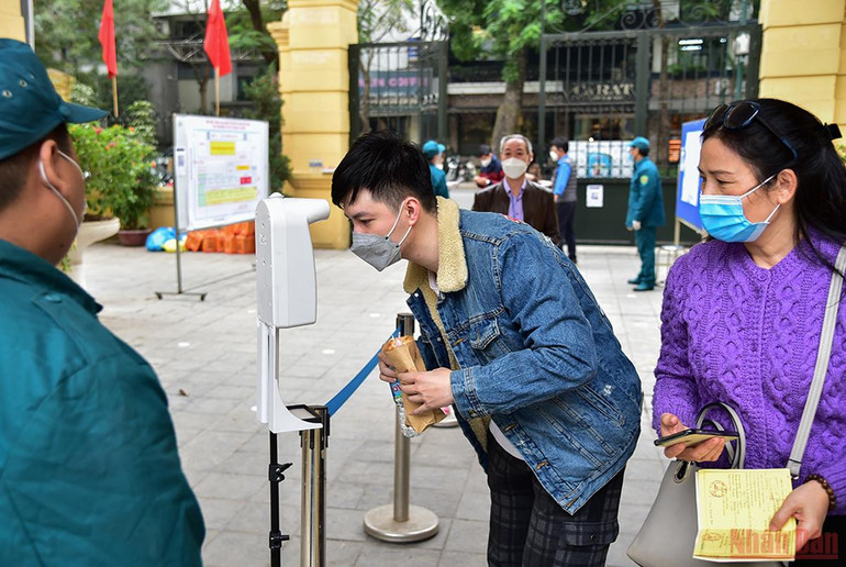 Người dân thực hiện kiểm tra thân nhiệt và quét mã QR khai báo y tế trước khi vào khu vực tiêm. Hà Nội đã tiêm hơn 1 triệu liều vaccine mũi bổ sung và nhắc lại -0