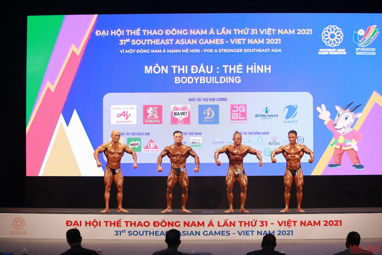 Lực sĩ Đặng Thanh Tùng (thứ hai từ trái sang) trong phần biểu diễn của mình. Đằng sau tấm Huy chương vàng thể hình của Đặng Thanh Tùng -0