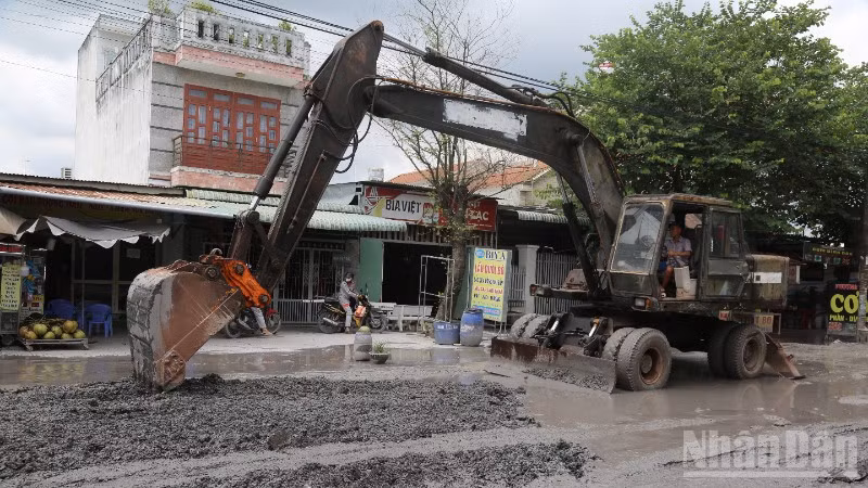 Đơn vị thi công dùng xe múc sửa chữa nền đường Bưng Môn.