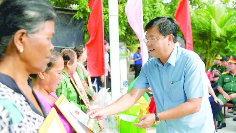 Bí thư Tỉnh ủy An Giang Nguyễn Tiến Hải trao quà tặng người dân tại lễ bàn giao nhà đại đoàn kết trong chương trình “Xóa nhà tạm, nhà dột nát”. (Ảnh QUỐC TRINH)