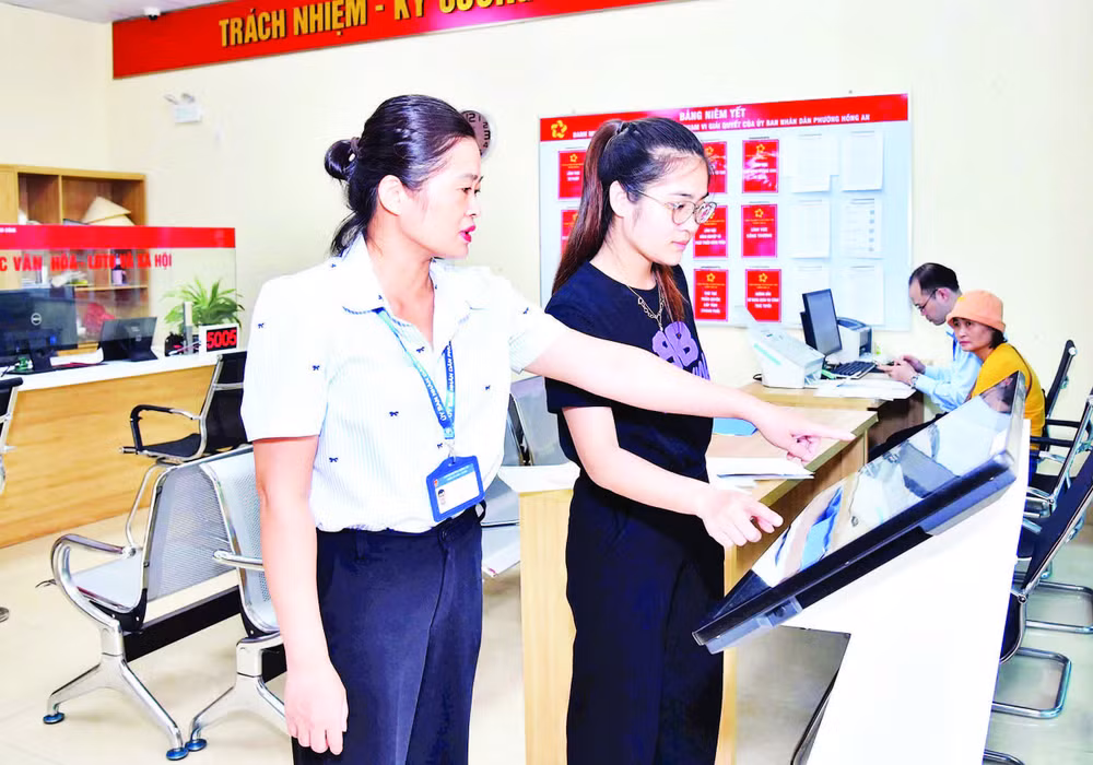 Cán bộ công chức Trung tâm Phục vụ hành chính công phường Hồng An, thành phố Hải Phòng hướng dẫn người dân thực hiện nộp hồ sơ trực tuyến. (Ảnh TRUNG KIÊN)