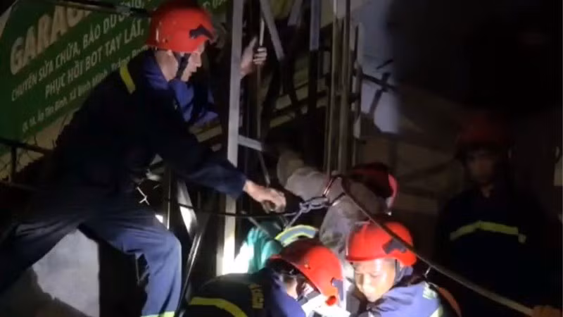 Lực lượng cứu hộ dùng dây, đai đưa ông T từ trên bảng quảng cáo xuống đất.