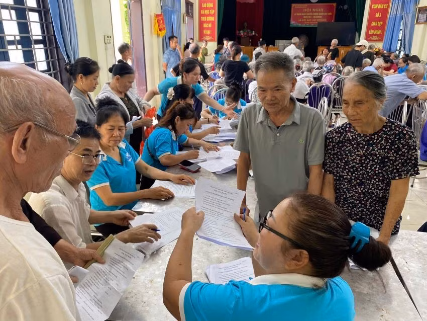 Hội Phụ nữ xã Ô Diên hướng dẫn người dân khai hồ sơ trợ cấp bảo hiểm xã hội. (Ảnh: DIỆU THƯƠNG)