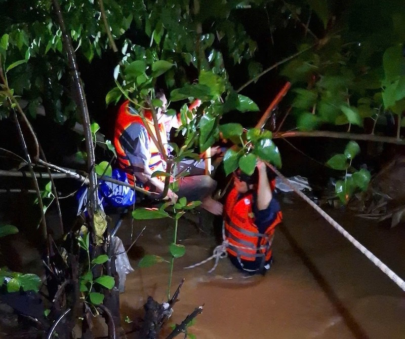 Người đàn ông bị nước cuốn may mắn bám vào cành cây được lực lượng chức năng ứng cứu kịp thời. (Ảnh: Công an cung cấp)