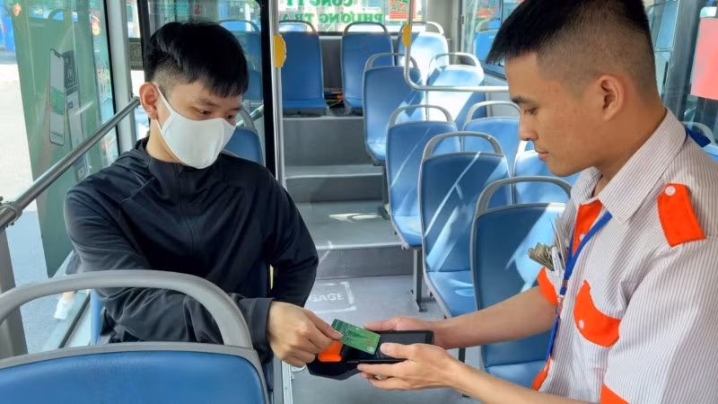 Hành khách thanh toán không dùng tiền mặt khi đi một số tuyến xe buýt của thành phố. (Ảnh: QUÝ HIỀN)