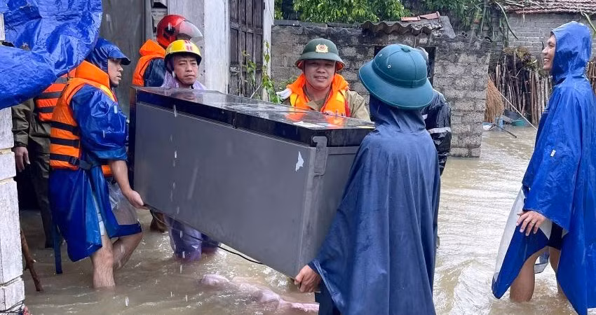 Lực lượng chức năng di dời tài sản của người dân ra khỏi vùng ngập nước.
