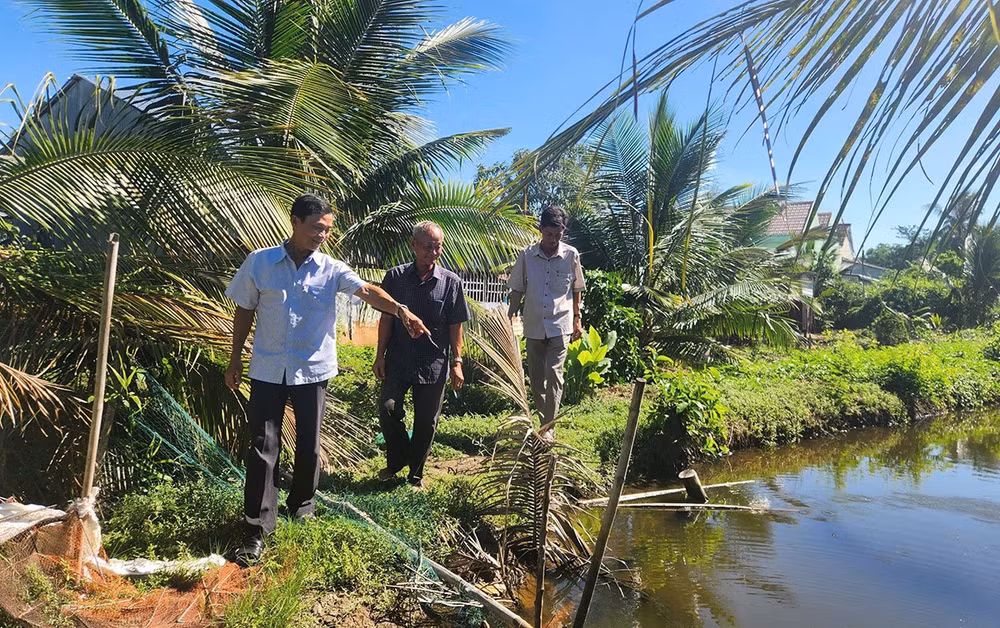 Ông Năm Dậu (giữa) cùng cán bộ địa phương đến tận nơi tìm hiểu, giải quyết ổn thỏa mâu thuẫn trong tranh chấp đất của hai hộ dân.