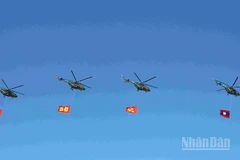 Đội hình máy bay trực thăng mang cờ Đảng, cờ Tổ quốc Lào trên bầu trời quảng trường That Luang. (Ảnh: DUY TOÀN)