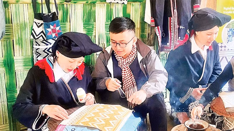 Du khách trải nghiệm nghề truyền thống vẽ sáp ong tại điểm du lịch cộng đồng bản Sưng, xã Cao Sơn.
