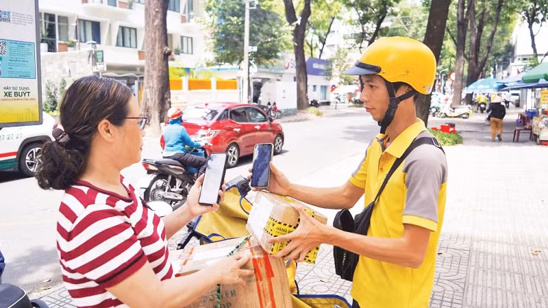 Khách hàng thanh toán không tiền mặt khi nhận hàng hóa trên đường Phạm Ngọc Thạch, Quận 3. (Ảnh THẾ ANH)