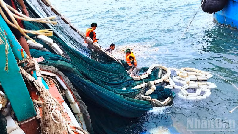 Cán bộ, chiến sĩ Đồn Biên phòng Hòn Chuối hỗ trợ trục vớt lưới đánh cá đưa lên tàu cứu nạn.