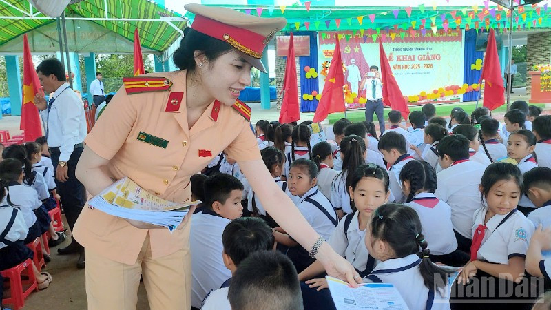 Cán bộ Cảnh sát giao thông phát tờ rơi tuyên truyền tại Trường tiểu học Tân Hưng Tây A, xã Nguyễn Việt Khái, tỉnh Cà Mau.