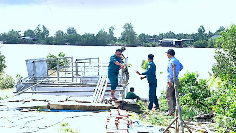 Lực lượng chức năng địa phương hỗ trợ tháo dỡ nhà bà Bích vốn bị nhấn chìm xuống sông sau vụ sạt lở.