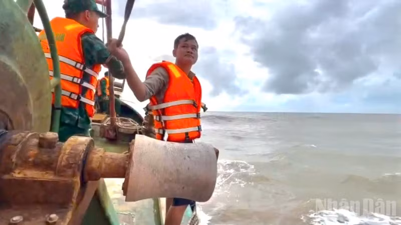 Một trong 2 thuyền viên (bìa phải) trên tàu cá gặp nạn được cán bộ, chiến sĩ Đồn Biên phòng Sông Đốc đưa lên tàu an toàn vào chiều muộn 29/9.